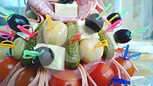 The original design of the appetizers on the table - pickles and olives, salami, tomatoes and cheese.