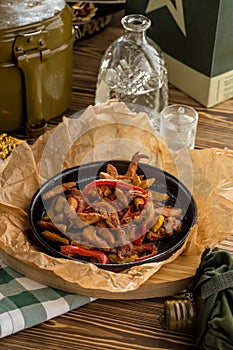 Original fajita sizzling smoking hot served on iron plate with vodka on wooden table