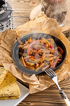 Original fajita sizzling smoking hot served on iron plate on wooden table