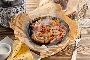 Original fajita sizzling smoking hot served on iron plate on wooden table