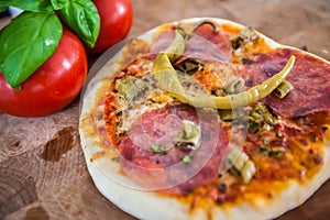 Original Italian Pizza alla diavolo on brown wood background. Pizza with Hot peppers and salami close up