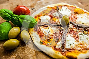 Original Italian Pizza Napoletana on brown wood background. Pizza with anchovies and capers close up