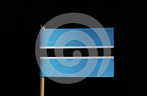 A original and official flag of Botswana on toothpick on black background. Flag consists from light blue field cut horizontally in