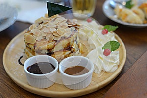 The Original pancakes with almonds and whipped cream on wood dish