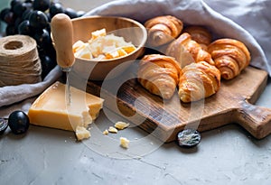 Original tasty French croissants with cheese and grapes on the wooden table. buttery flaky viennoiserie bread roll distinctive