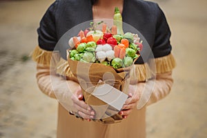 The original unusual edible vegetable and fruit bouquet with card in woman hands