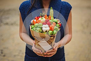 The original unusual edible vegetable and fruit bouquet with card in woman hands