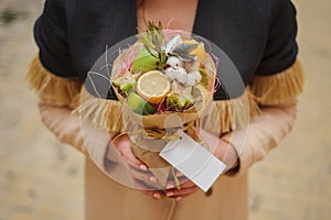 The original unusual edible vegetable and fruit bouquet with card in woman hands