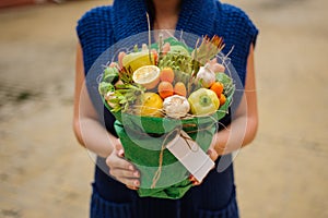 The original unusual edible vegetable and fruit bouquet with card in woman hands