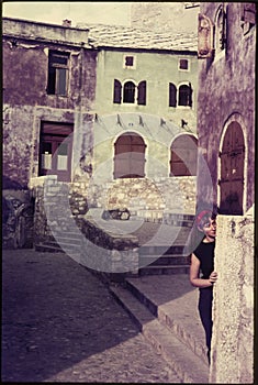 Original vintage colour slide from 1960s, young woman hiding behind a wall.