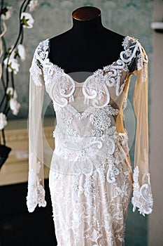 Original wedding lace embroidered dress with long sleeves on a black mannequin