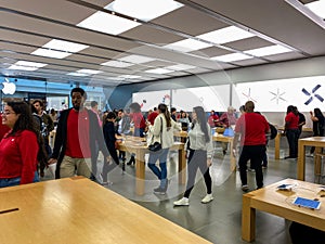 An Apple store with people waiting to purchase Apple Macbooks, iPads and iPhones