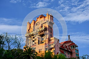 The Twilight zone Tower of Terror and palm trees on lightblue cloudy sky background in Hollywood Studios at Walt Disney World .