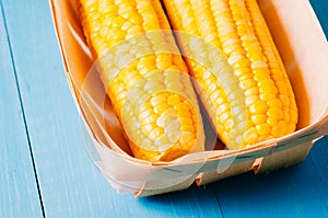 ÃÂ¡orn. Fresh yellow corn on wooden blue table closeup. Selective focus. Yellow corn in small basket on blue wooden background