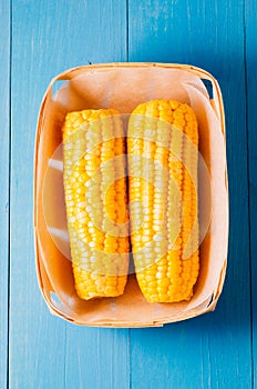ÃÂ¡orn. Fresh yellow corn on wooden blue table closeup. Top view. Yellow corn in small basket on blue wooden background