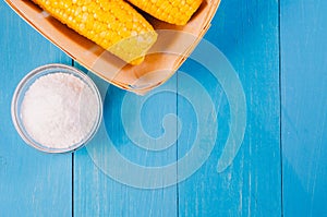 Ð¡orn with salt. Top view and copy space. Yellow corn in small basket and salt glass on blue wooden background