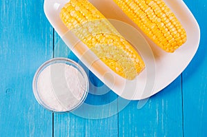 Ð¡orn with salt. Top view. Yellow corn in a white bowl and salt glass on blue wooden background