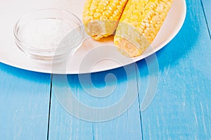 Ð¡orn with salt. Top view. Yellow corn in a white bowl and salt glass on blue wooden background