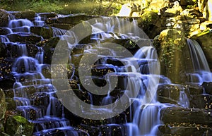 Ornamental Cascade waterfall with visible sun rays - Virginia Water, Surrey, United Kingdom