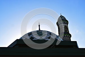 Ornamental dome of the mosque with minaret against blue sky