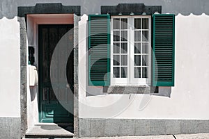 Ornamental facade of colorful house in Sao Miguel, Azores. Portugal. Beautiful old tiny houses, green doors and window