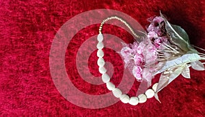 Ornamental flowers and white necklaces on a red fluffy carpet background