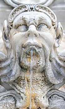 ornamental sculpture of a human head gushing liquid from the mouth