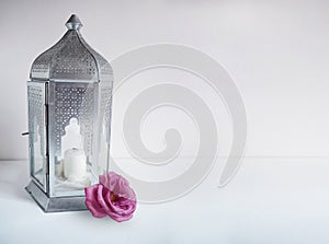 Ornamental silver Arabic lantern with rose flower on the table. Greeting card, invitation for Muslim community holy