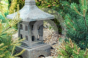 Ornamental stone lantern with among fresh green plants japanese design, outdoor garden stone statue decoration