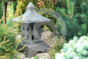 Ornamental stone lantern with among fresh green plants japanese design, outdoor garden stone statue decoration