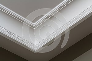 Ornamental white molding decor on ceiling of white room close-up detail. Interior renovation and construction concept.