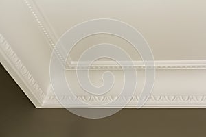 Ornamental white molding decor on ceiling of white room close-up detail. Interior renovation and construction concept.