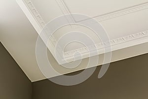 Ornamental white molding decor on ceiling of white room close-up detail. Interior renovation and construction concept.
