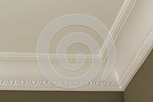 Ornamental white molding decor on ceiling of white room close-up detail. Interior renovation and construction concept.