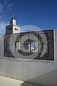 Ornamental windows on roof top terrace with mosque tower in Tunisia