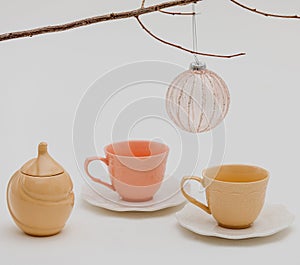 an ornamented toy ball, colorful cups with saucers, and a sugar-bowl