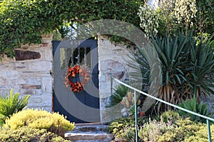 Ornate blue wooden garden gate set in a Carmel stone wall, Old Monterey California.