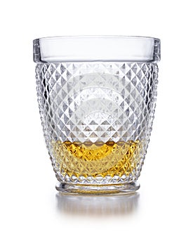 An ornate  crystal glass containing scotch whisky shot on white, with a slight drop shadow