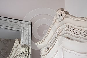 Ornate decor including a large wardrobe and equally ornate mirror.