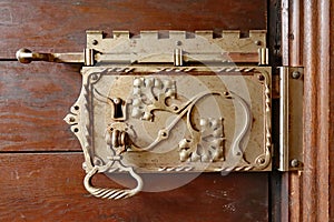 An ornate door lock mechanism decorated with vines and leaves in an English country house