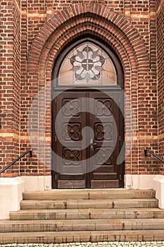 an ornate double wooden door with brickwork and arched glass