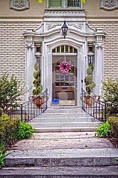 Ornate entrance to vintage luxury upscale home with landscaping and door wreath and package delivered on porch