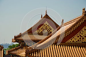 Ornate gold and red paintwork on roofs of traditional Chinese buildings