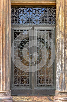 Ornate iron door framed by vertical fluted columns
