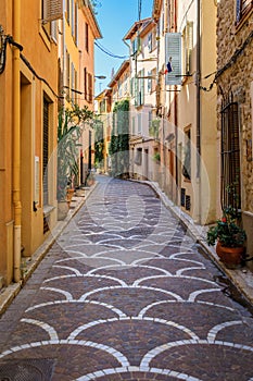 Ornate mosaic street pavement between traditional old houses in Antibes, France