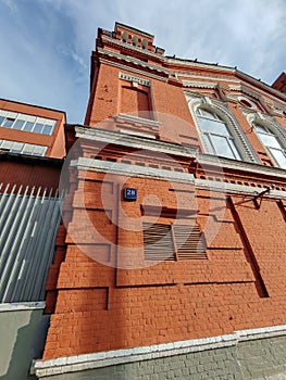 An ornate red brick structure with arched windows, white decorative elements, and shadows cast along its textured facade photo