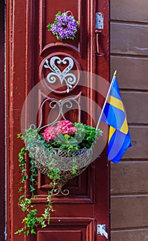 Ornate red door decorated with a Swedish flag and a flower pot i