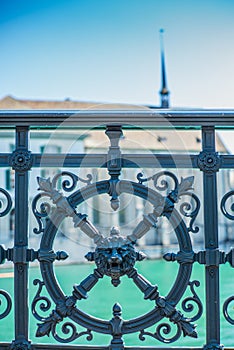 The ornated wrougth iron handrail on the Limmat riverside in Zurich with the Wasserkirche in the background  - 2