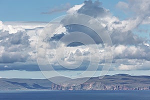 Orney cliffs with dramatic sky seen from John o`Groats over Atlantic ocean