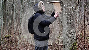 Ornithologist with bird house near tree